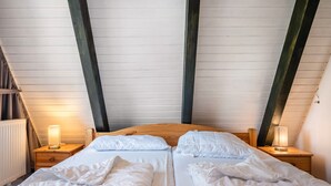 Un dormitorio con dos camas, cabeceros de madera y lámparas de noche.