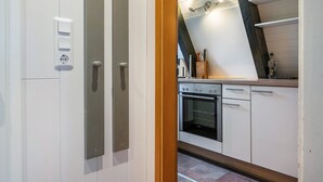 Una cocina con alacenas blancas, horno empotrado y encimera con varios utensilios de cocina.