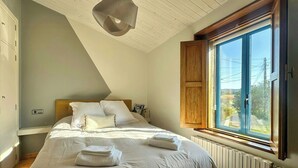 A bedroom with a bed, a window with wooden shutters, a radiator, and a ceiling light fixture. - Galician stone house with hórreo and garden (Bustelo)
