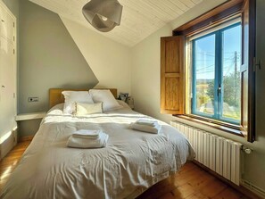 Ein Schlafzimmer mit einem Bett, einem Fenster mit Holzjalousien, einem Heizkörper und einer Deckenleuchte.