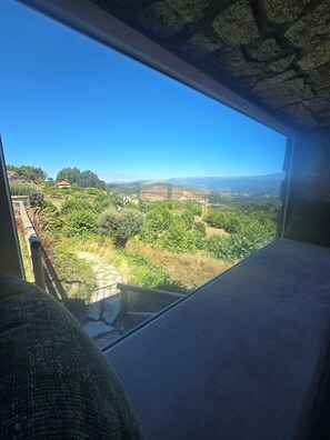 Ein Zimmer mit einem großen Fenster mit Blick auf eine Landschaft mit Bäumen und einem entfernten Gebäude.