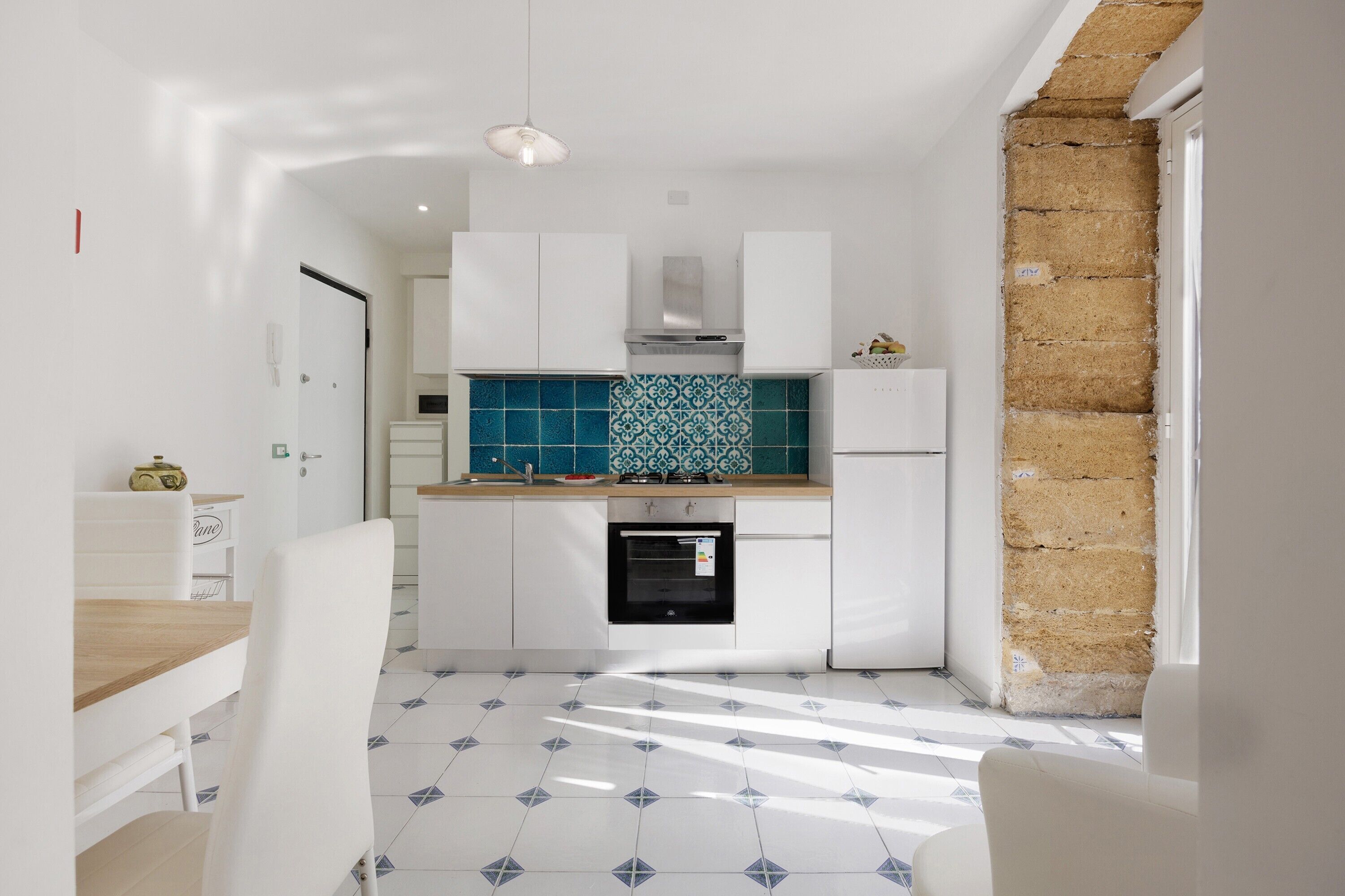 A compact kitchen with white cabinets, a tiled backsplash, and a built-in oven.