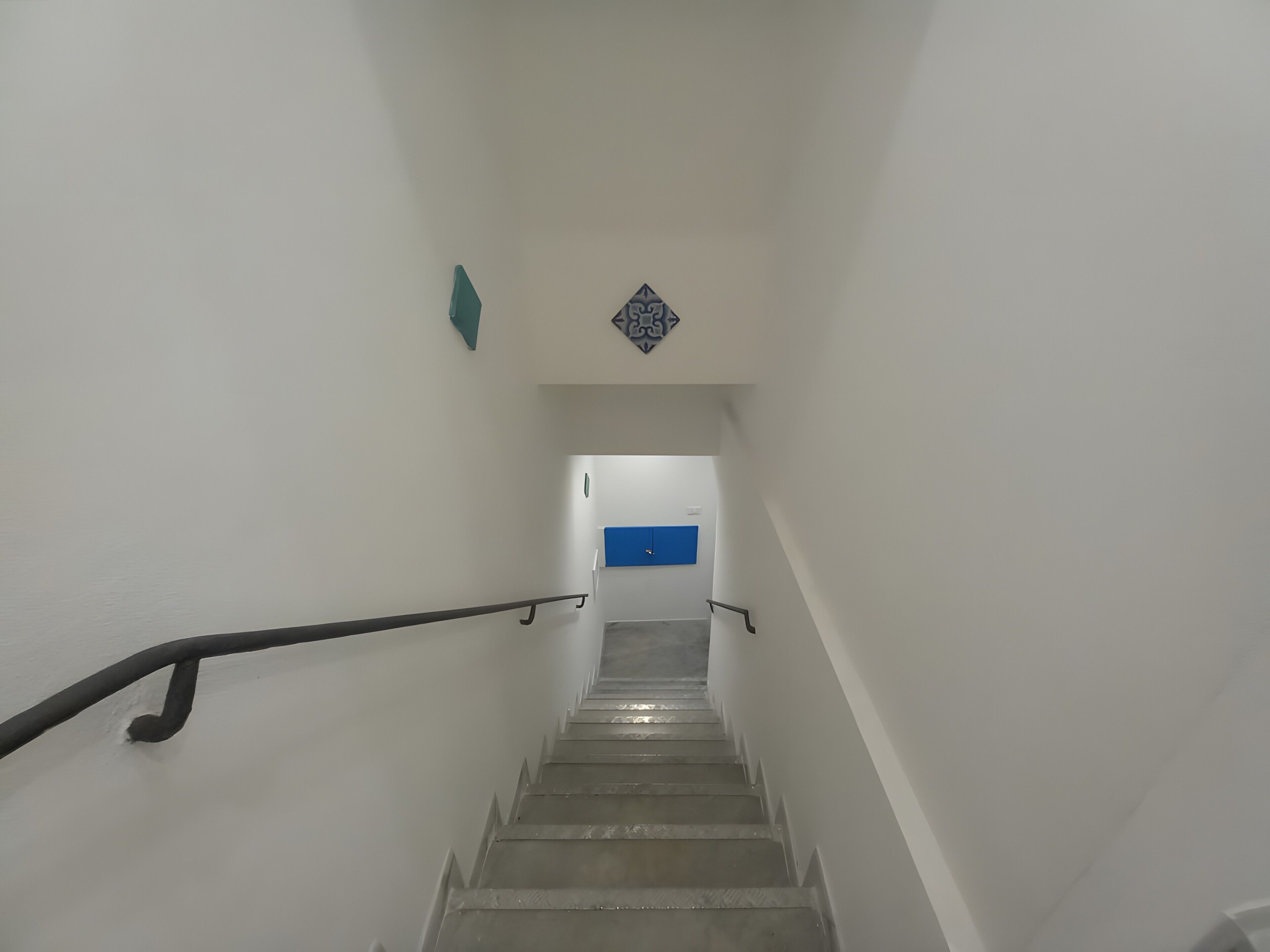 A staircase with handrails, leading to a room with a blue accent wall.