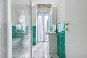 Une salle de bain avec une paroi en verre, des toilettes, un lavabo et un espace douche.