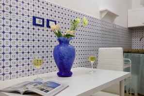 Ett bord med en blå vas som innehåller blommor, två glas vitt vin och en tidning.