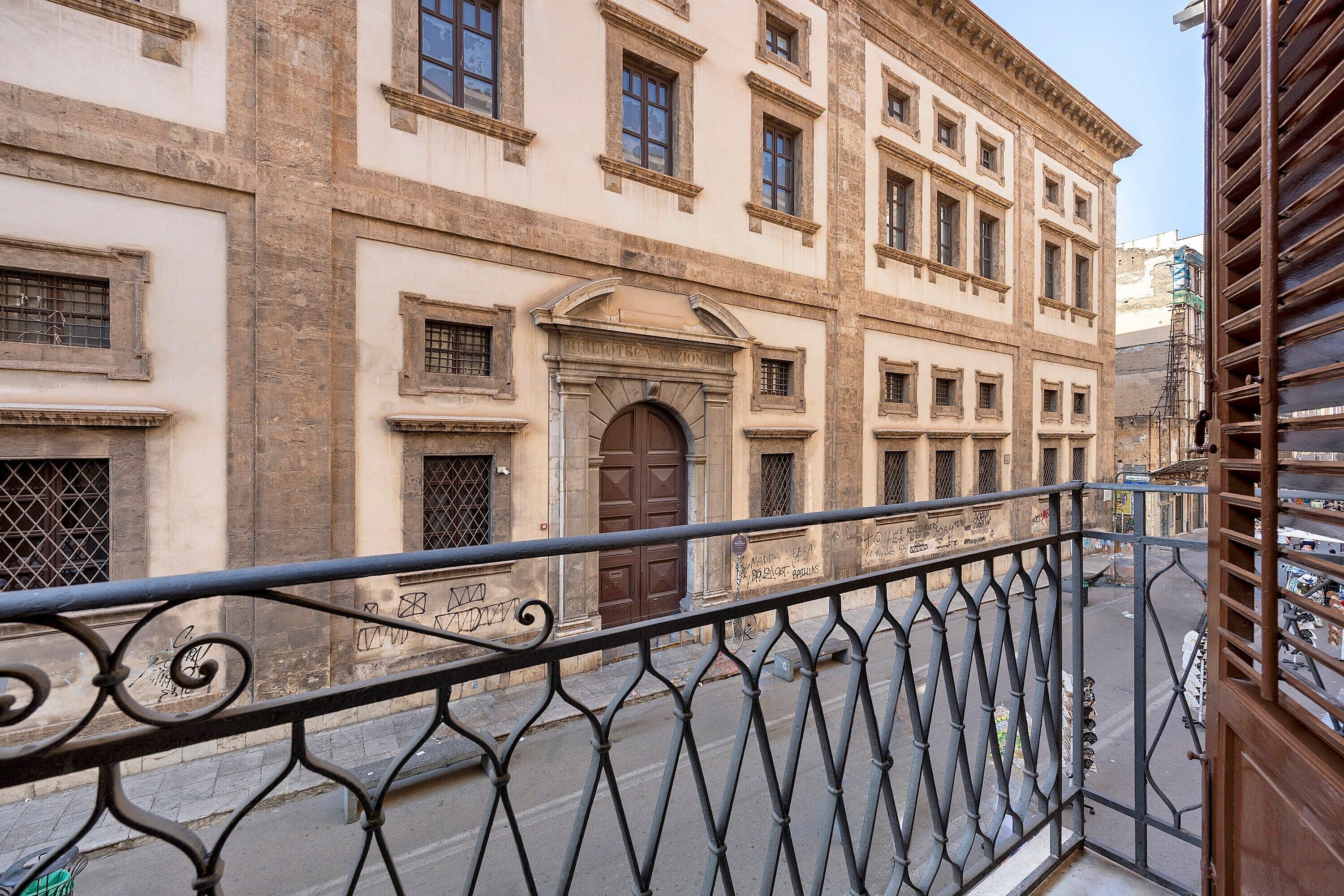 A building with a classical architectural style, featuring a prominent entrance with a large door and a balcony with ornate metal railings.
