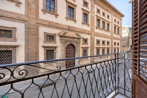 A building with a classical architectural style, featuring a prominent entrance with a large door and a balcony with ornate metal railings. - Apartment 'Le Stanze Del Sole - Blu' with Balcony and Air Conditioning (Palermo)
