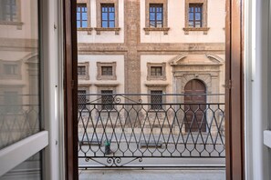 Blick durch ein Metallgitter auf ein Gebäude mit zahlreichen Fenstern und einer zentralen Tür, auf der 'BIBLIOTECA NAZIONALE' steht.