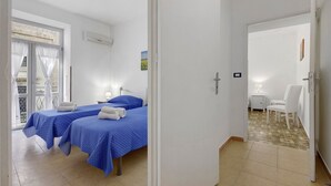 Ein Hotelzimmer mit zwei Betten, einem Balkon und einer Essecke.