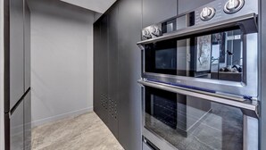 Eine moderne Küche mit Edelstahlgeräten, darunter ein Doppelbackofen und eine Mikrowelle.