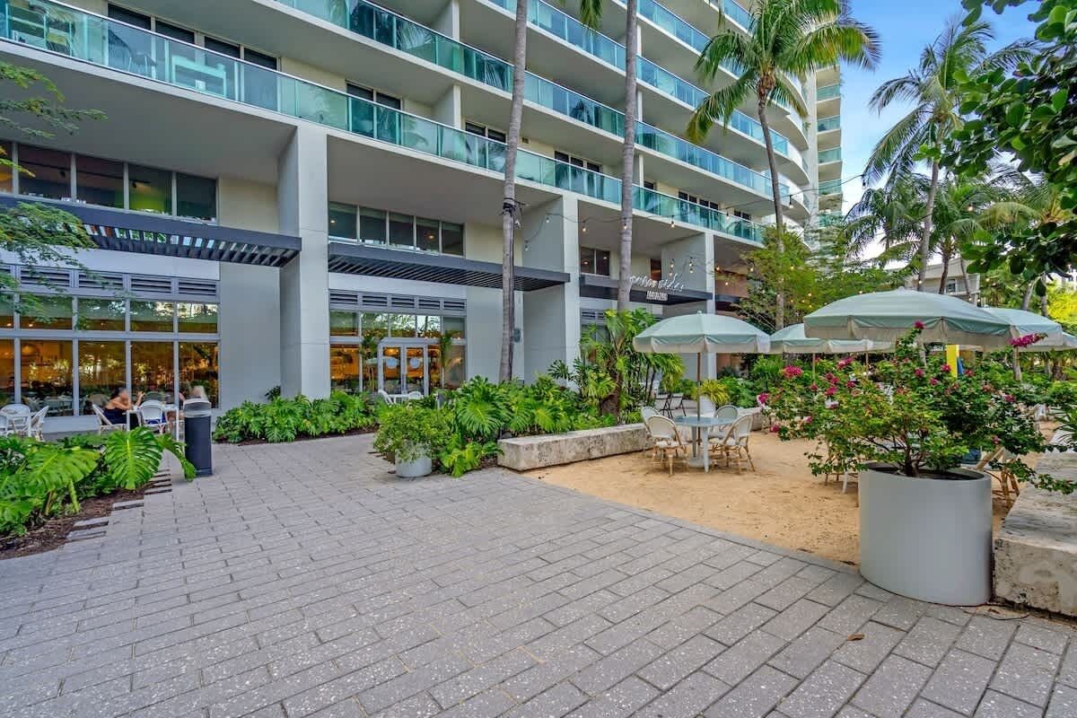 A hotel with a modern design, outdoor seating area, and palm trees.