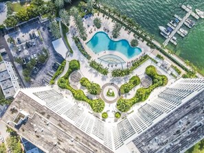 Ein Hochhaus-Hotel mit Pool, Parkplätzen und Blick auf das Wasser.