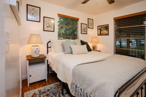 A bedroom with a bed, bedside tables, lamps, and framed floral artwork on the walls.