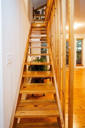 A wooden staircase with a railing, leading to a landing area with a plant. - Old Place Inverness - 1926 Farmhouse (Inverness)