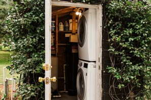 A laundry room with a washing machine and shelves of cleaning supplies.