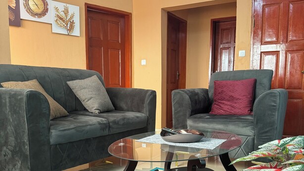Ein Wohnzimmer mit zwei grauen Sofas, einem Glastisch und einem gemusterten Teppich.