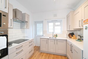 A modern kitchen with white cabinetry, a built-in oven, and a window above the sink. - Beautifully Refurbished 2Bed Flat in East Finchley - Pass the Keys (London)