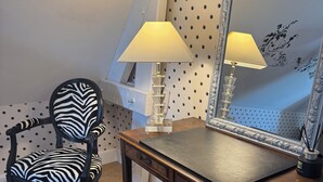 Ein Zimmer mit Schreibtisch, Stuhl, Lampe, Spiegel und einer Wand mit Punkten.