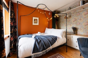 A bedroom with a bed, a desk, a chair, and a wall with a floral pattern. - Artful Hoxton Flat with Private Balcony - Pass the Keys (London)