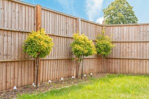 A wooden fence with evenly spaced trees and small lamps along the bottom.