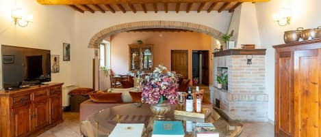 A living room with a glass coffee table, wooden cabinets, a television, and a fireplace.