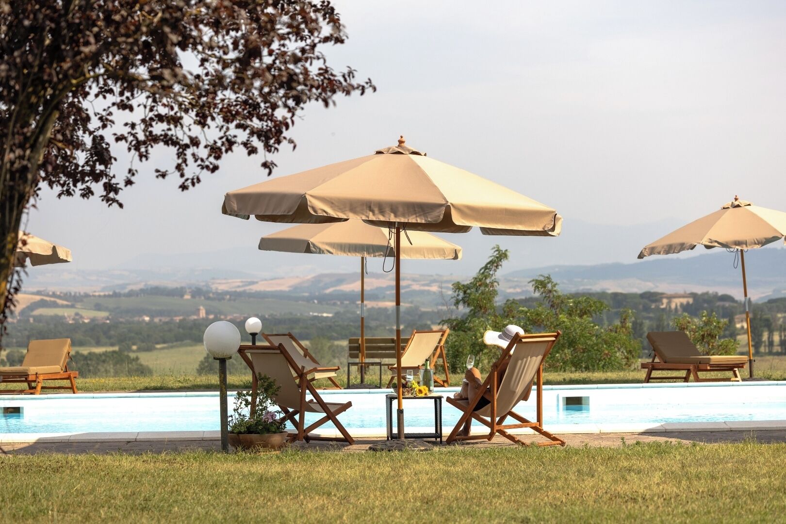 A poolside area with lounge chairs and umbrellas, overlooking a scenic landscape.