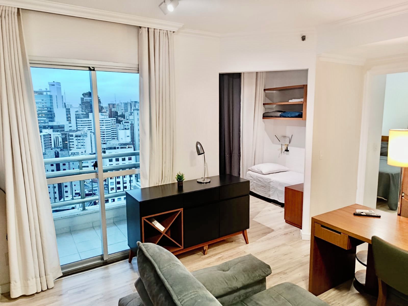 Ein modernes Hotelzimmer mit Blick auf die Stadt, inklusive Bett, Schreibtisch und Sofa.