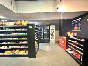 Interior de un supermercado con estantes llenos de bocadillos y bebidas, una sección refrigerada y una exhibición de la marca Kibon.
