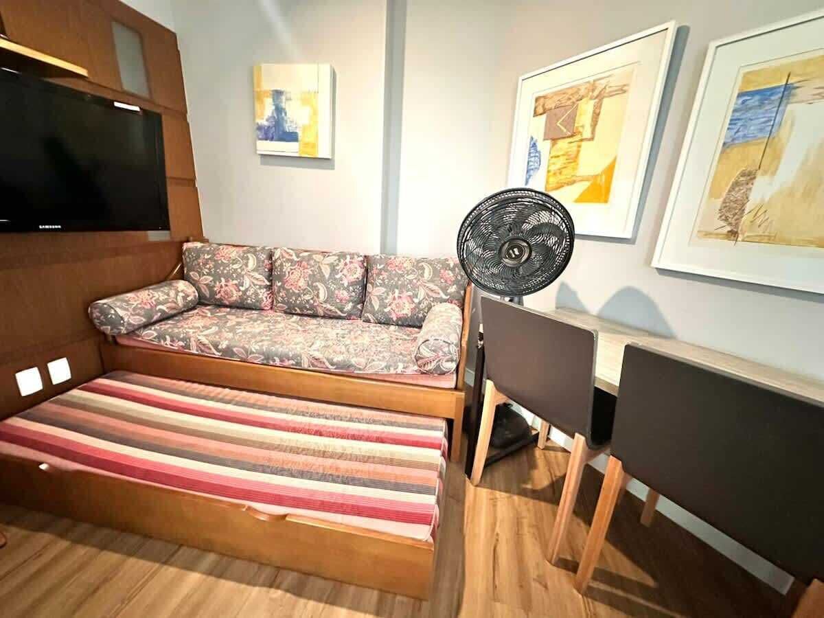 Una habitación con sofá, ventilador, televisión y obras de arte en las paredes.