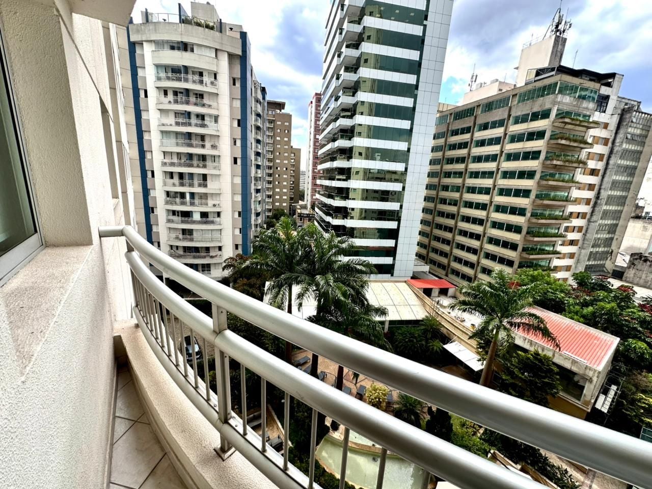 A balcony with a view of high-rise buildings and palm trees.