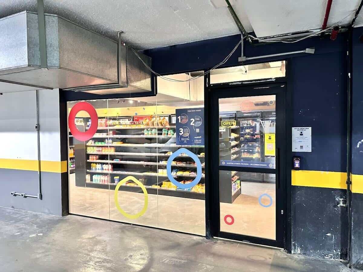 Ein Laden mit Glastür, einem Schild, das die Öffnungszeiten anzeigt, und einem sichtbaren Kassenbereich.