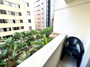Un balcón con vista a una zona residencial, con edificios y una fila de palmeras.