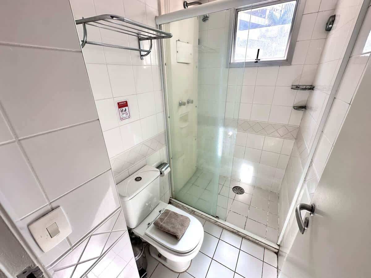 Kylpyhuone, jossa on wc, lasiseinällä varustettu suihku ja ikkuna.