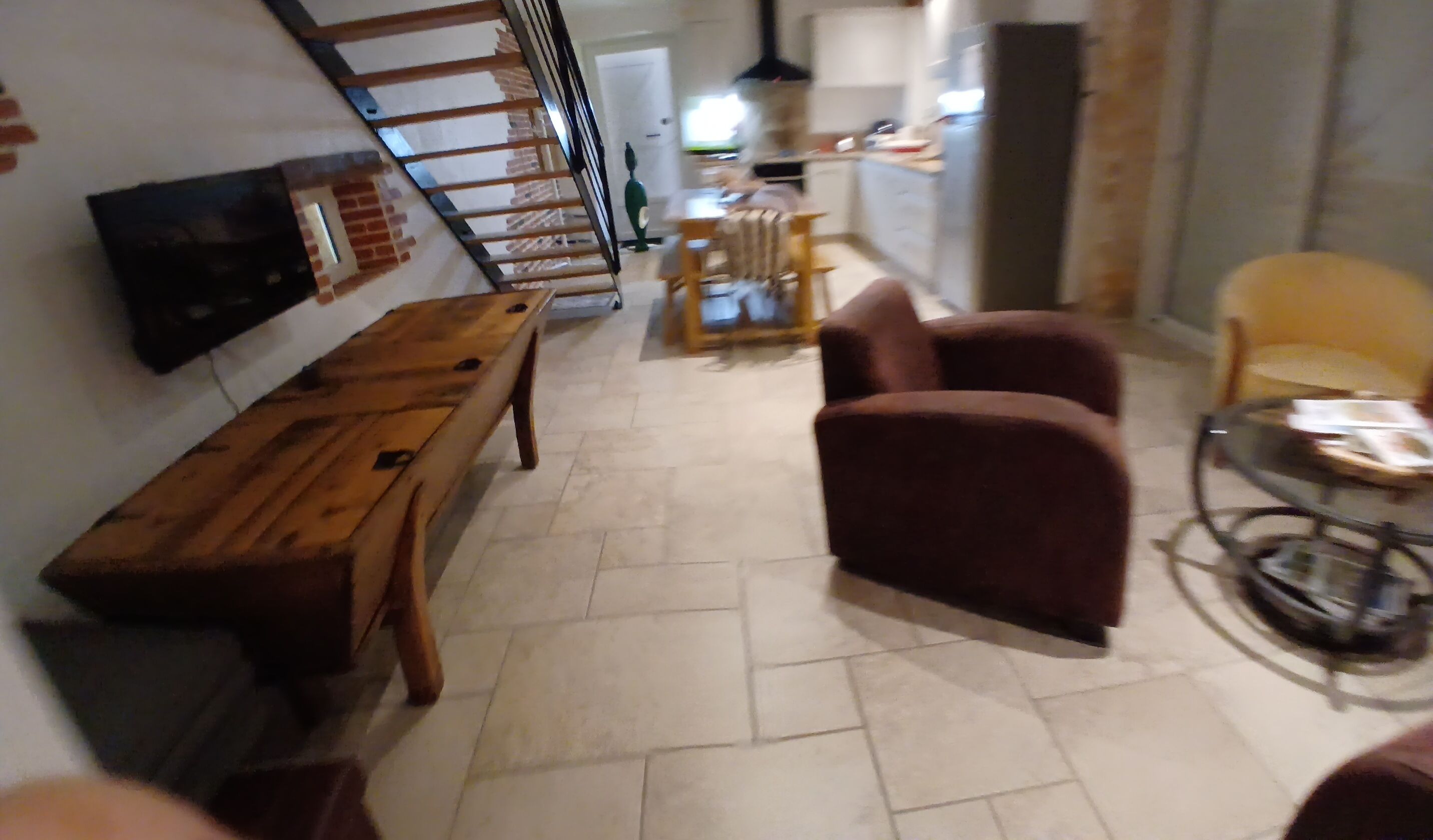 Un soggiorno con una panca di legno, un divano, una TV montata a parete e una scala che conduce a un altro piano.