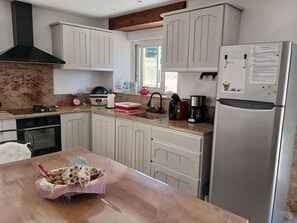 A modern kitchen with white cabinetry, a stainless steel refrigerator, a coffee maker, and a kettle. - L'Establou Farm Stay (COLY ST AMAND)