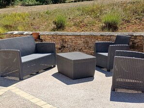 Outdoor wicker furniture arranged around a stone wall. - L'Establou Farm Stay (COLY ST AMAND)