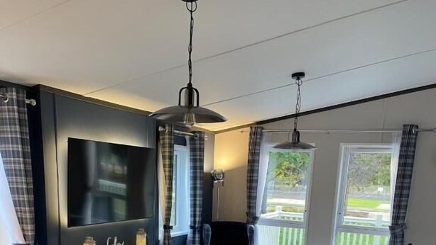 Uma sala de estar moderna com televisão de tela plana, lareira e um conjunto de sofás.