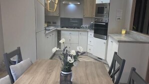 Uma cozinha moderna com uma mesa de jantar, cadeiras e um vaso de flores.