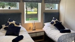 A hotel room with two beds, a nightstand, a window with a view, and a ceiling light.