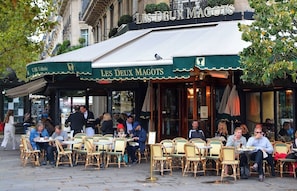 An outdoor cafe with outdoor seating and a covered awning. - COMBINATION OF PARISIAN ARCHITECTURE WITH MODERN COMFORT - RUE DE RENNES (Paris)