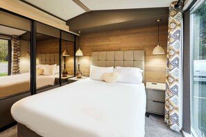 Ein Hotelzimmer mit einem großen Bett, Nachttischen, einem Spiegel und einem Fenster mit Vorhängen.