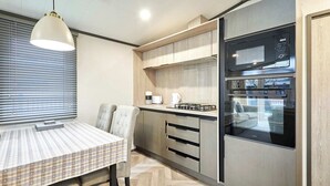 Una cocina moderna con horno y microondas integrados, una mesa de comedor con sillas y una lámpara colgante.