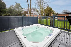 A hot tub on a wooden deck with a dark fence and trees in the background. - Host & Stay | Molly's Retreat (Pocklington)