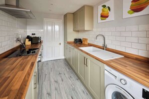 Eine kleine Küche mit integriertem Waschmaschine, Spüle und Holz Arbeitsplatten.