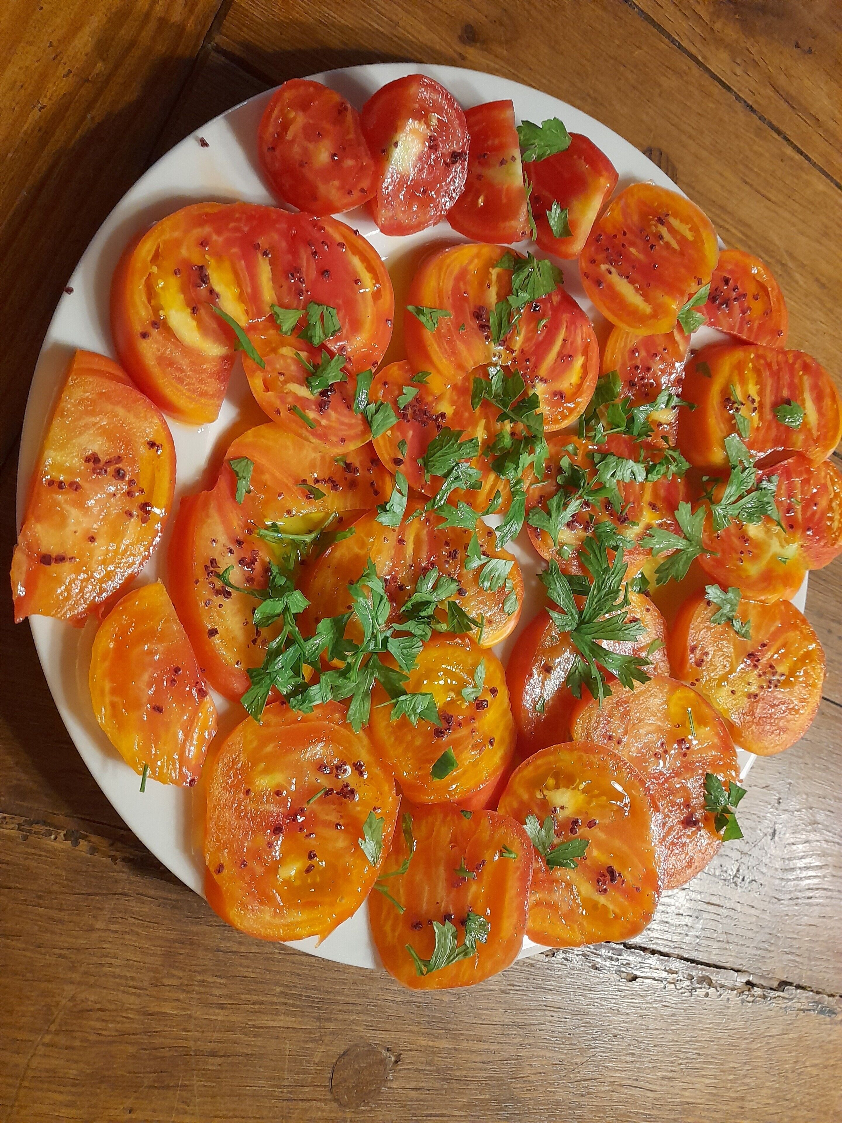 A plate of sliced tomatoes garnished with herbs.