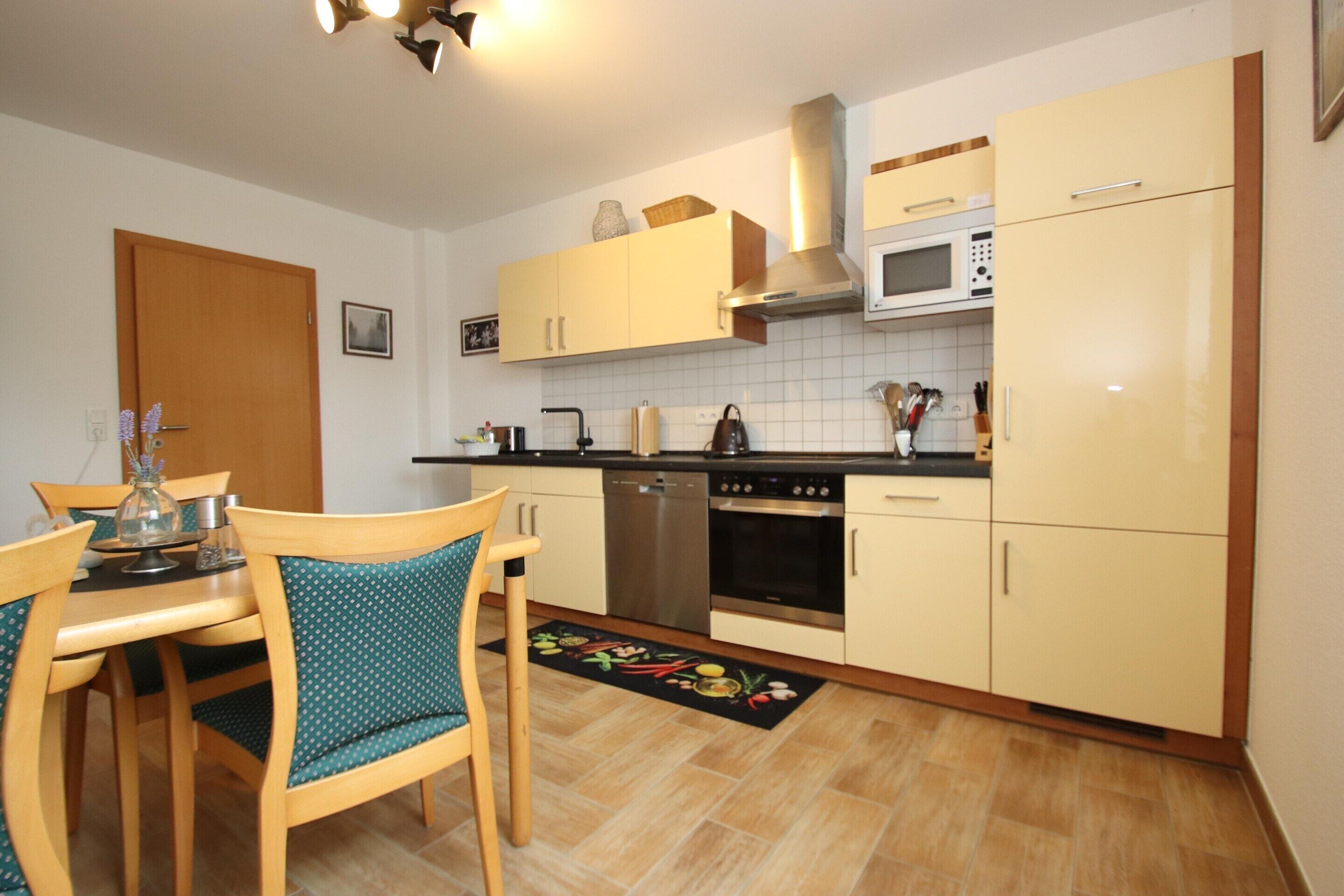 A compact kitchen with a dining area, featuring a microwave, stove, and cabinets.