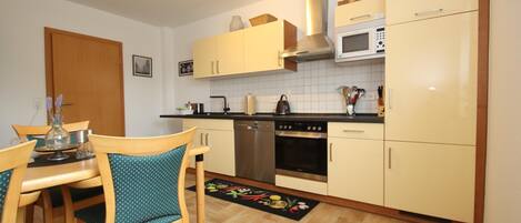A compact kitchen with a dining area, featuring a microwave, stove, and cabinets.