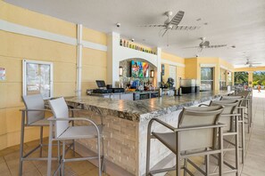 A bar area with a counter, bar stools, and a tiled backsplash. - Beautiful Vista Cay Condo Next to Clubhouse - 3033 (Orlando)