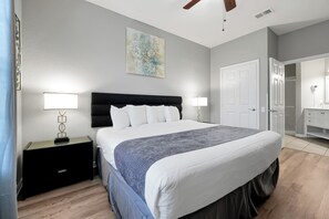 A bedroom with a bed, nightstands, a ceiling fan, a painting, and a walk-in closet. - Beautiful Vista Cay Condo Next to Clubhouse - 3033 (Orlando)