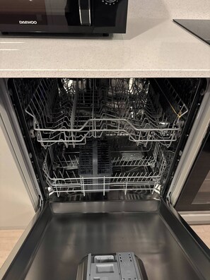 An open dishwasher with multiple racks and a control panel above. - Apartment in Botanical Gardens, Old Trafford (Manchester)